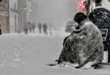 Activists Urge Sheriff Asbell to Halt Evictions homeless person sitting on the street covered in snow