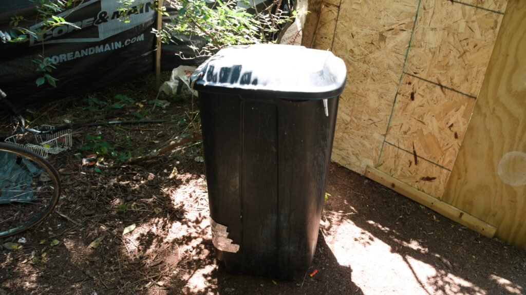 Trash can at homeless encampment